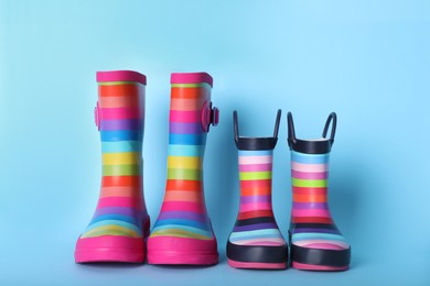 Two pairs of striped rubber boots on light blue background