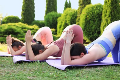 Young women practicing yoga on mats outdoors