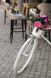 Retro bicycle with flowers in basket on outdoor terrace