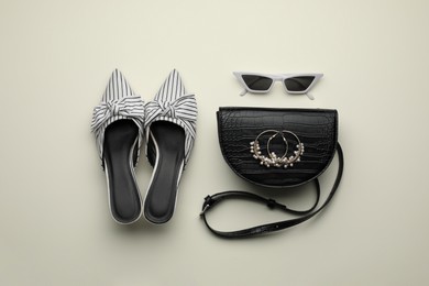 Stylish woman's bag, shoes, earrings and sunglasses on light background, flat lay