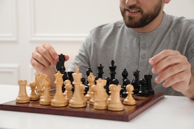 Man playing chess at white table indoors, closeup