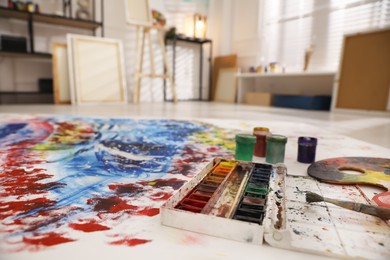 Paints and brush on abstract picture in art studio with easel