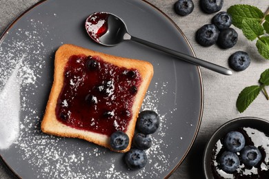 Delicious toast served with jam and blueberries on grey wooden table, flat lay