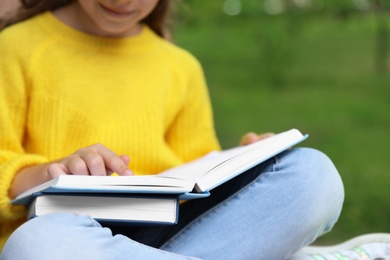 Little girl reading book in park, closeup