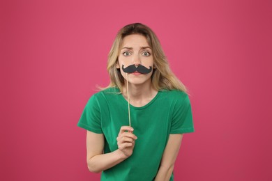 Photo of Young woman with fake mustache on pink background