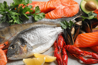 Fresh fish and different seafood on light grey table, closeup