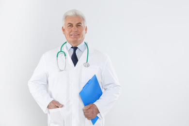 Portrait of senior doctor with stethoscope and clipboard on white background