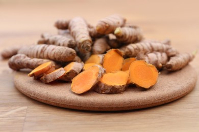 Photo of Board with fresh turmeric roots on wooden table
