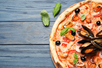 Tasty pizza with seafood and fresh basil on blue wooden table, flat lay. Space for text