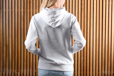 Photo of Woman in hoodie sweater on wooden background. Space for design