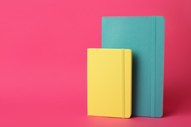 Stylish colorful planners on pink background. Space for text