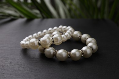 Elegant pearl bracelets on black table, closeup