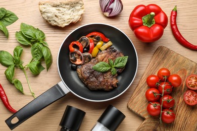 Photo of Flat lay composition with delicious steak and vegetables in frying pan on wooden table