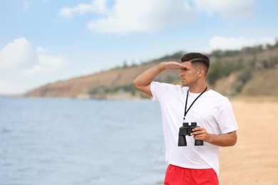 Handsome male lifeguard with binocular near sea