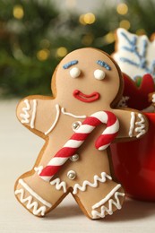 Gingerbread man and delicious homemade Christmas cookies on white wooden table against blurred festive lights