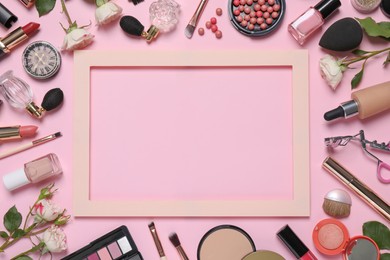 Flat lay composition with different makeup products and frame on pink background, space for text