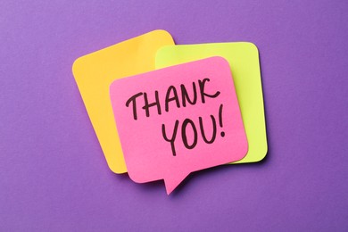 Pink paper note with phrase Thank You on purple background