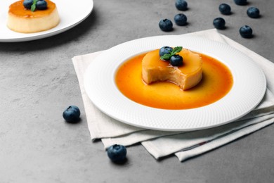 Photo of Delicious puddings with caramel and blueberries on grey table