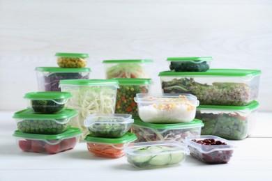 Set of plastic containers with fresh food on white wooden table