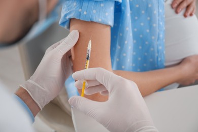 Doctor vaccinating pregnant woman against coronavirus in clinic, closeup