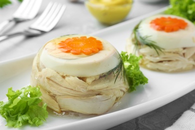 Delicious chicken aspic with eggs and vegetables on plate, closeup