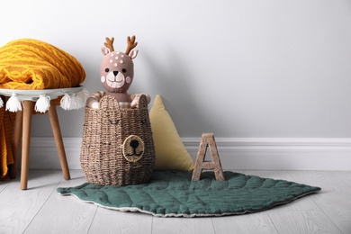 Wicker basket with cute toy deer in baby room, space for text. Interior design