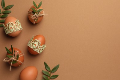 Photo of Festively decorated chicken eggs on brown background, flat lay and space for text. Happy Easter