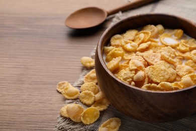 Tasty cornflakes with milk in bowl served on wooden table, closeup. Space for text