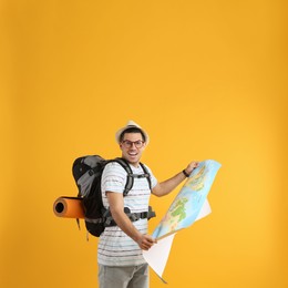 Excited male tourist with travel backpack and map on yellow background