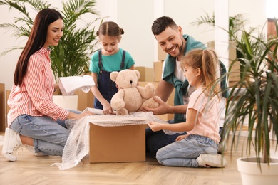 Happy family unpacking moving box in new house
