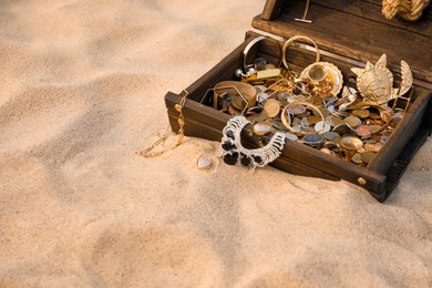 Open wooden treasure chest on sand, space for text