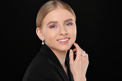 Photo of Beautiful young woman with elegant jewelry on black background