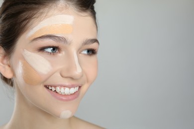Beautiful girl on grey background, closeup. Using concealer and foundation for face contouring