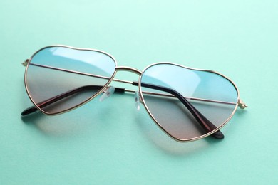 Stylish heart shaped sunglasses on light blue background