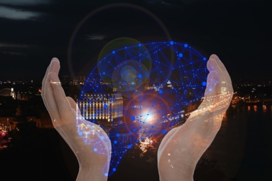 Image of Man holding digital image of brain in hands and night cityscape on background, closeup. Machine learning concept 