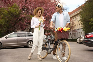 Photo of Lovely couple with bicycle and flowers on city street