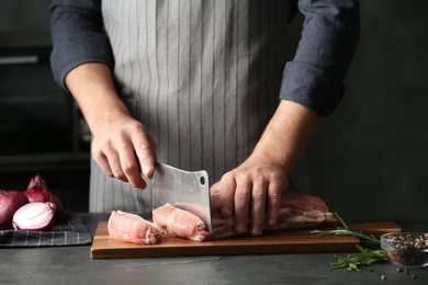 Photo of Man cutting fresh raw meat on grey table, closeup