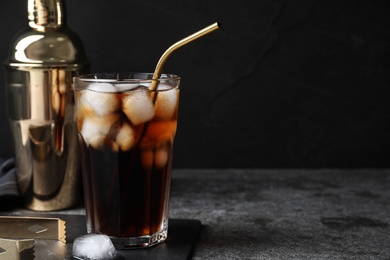 Tasty cola with ice cubes on grey table against dark background, space for text