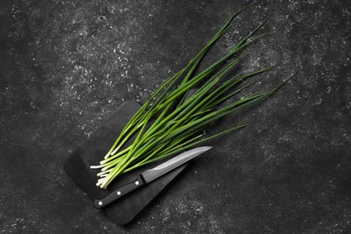 Fresh green onion and knife on black table, top view. Space for text