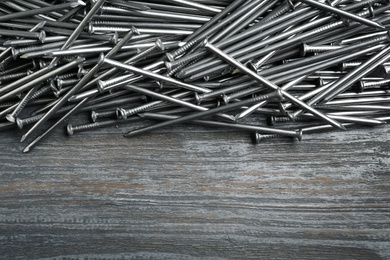 Photo of Many metal nails on wooden background, above view. Space for text