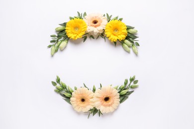 Wreathes made of beautiful flowers and green leaves on white background, flat lay. Space for text