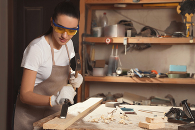 Professional carpenter working with wooden plank in workshop