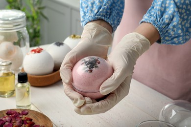 Woman in gloves making bath bomb at white table , closeup