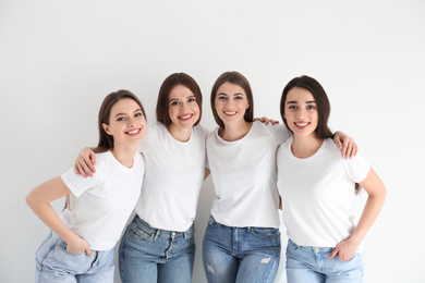 Beautiful young ladies in jeans and white t-shirts on light background. Woman's Day
