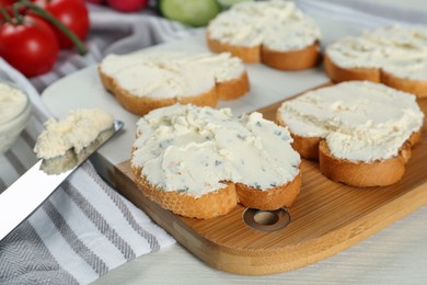 Toasted bread with cream cheese on white wooden table, closeup