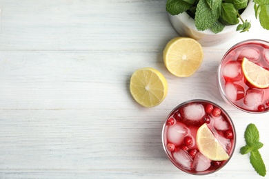 Tasty refreshing cranberry cocktails with lemon on white wooden table, flat lay. Space for text