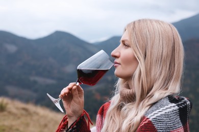 Young woman drinking wine in peaceful mountains