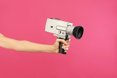Woman with vintage video camera on crimson background, closeup of hand