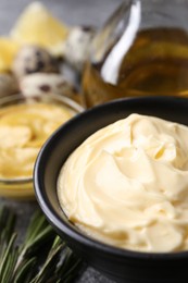 Photo of Delicious homemade mayonnaise with ingredients on grey table, closeup