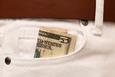 Dollar banknote in pocket of white jeans, closeup. Spending money